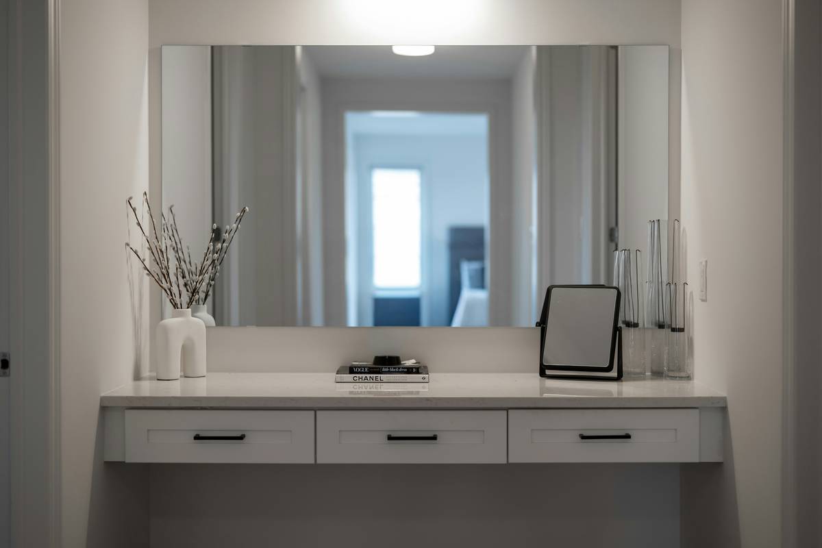 A minimalist chic vanity with integrated lighting, matte black legs, and organized drawers holding makeup brushes and skincare bottles