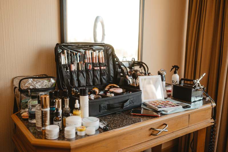 Side view of a curated vanity setup: white oak makeup table with soft LED ring light, rose quartz roller holder, and minimalist brush organizer